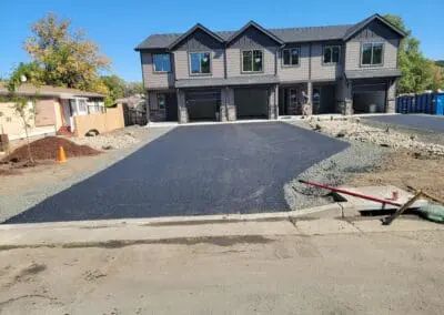 Newly paved driveway in front of three-unit modern townhouse development
