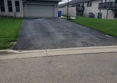 Suburban driveway with garage, portable basketball hoop, and green lawn