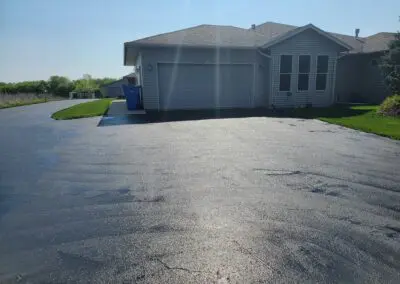 Suburban duplex garage with driveway, green lawn, and blue recycling bin