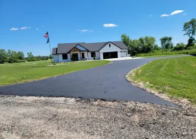 Modern white farmhouse with garage, driveway, flagpole, and grassy lawn
